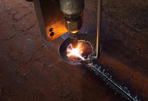 Plasma laser cnc industrial machine cutting iron and steel in metalwork workshop.